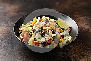 Mexican style salad of black beans, lentils, corn, tomato and lettuce with a salsa and tortilla chips