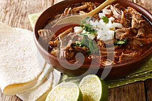 Mexican style slow cooked beef stew Birria de Res served with lime and tortilla closeup in a bowl. horizontal photo