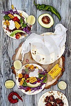 Mexican tacos with avocado, slow cooked meat, grilled corn, red cabbage slaw and chili salsa on rustic stone table. photo