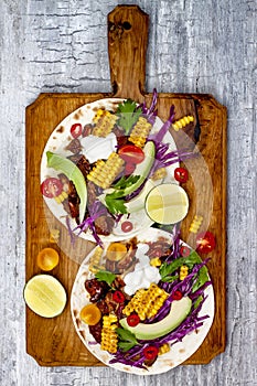 Mexican tacos with avocado, slow cooked meat, grilled corn, red cabbage slaw and chili salsa on rustic stone table. photo