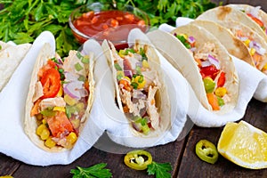 Mexican tacos with meat, corn, tomatoes, sweet pepper, red onions in a wheat tortilla