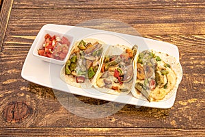 Mexican tacos of nopales, mushrooms and vegetables with fundos cheese and pico de gallo on white tray photo