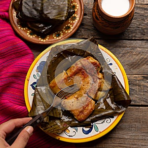 Mexican tamales in banana leaves on wooden background