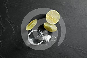 Mexican Tequila shot, lime slices and salt on black table, flat lay