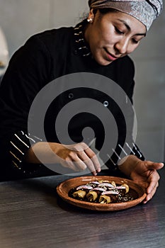 Mexican woman cooking mole poblano enchiladas traditional food in a restaurant in Mexico