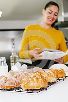 Mexican woman cooking Pan de muerto traditional bread for day of the dead in Mexico, Holding a recipe book