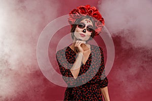 Mexican woman in la muerta attire and skull makeup during halloween with smoke. photo