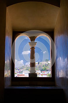 Mexico Oaxaca Santo Domingo monastery view from window with column to town and clouds