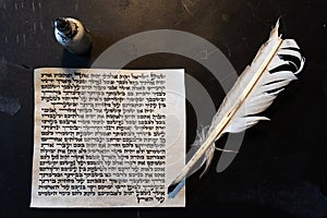 Mezuzah parchment made from animal skin with the full text of the Shema Yisrael Jewish prayer in Hebrew and the feather quill and photo