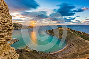 Mgarr, Malta - Panorama of Gnejna bay, the most beautiful beach in Malta at sunset with beautiful colorful sky photo