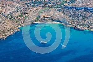 Mgiebah Bay, secluded cove accessible by a steep, rocky path, with a sandy beach and azure turquoise blue water. Mellieha, Malta.