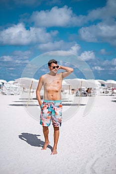 Miami beach Florida, young men on the beach with colorful lifeguard hut, man walking on the beach in Miami during