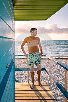 Miami beach Florida, young men on the beach with colorful lifeguard hut, man walking on the beach in Miami during