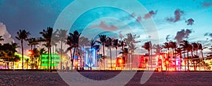 Miami Beach Ocean Drive panorama with hotels and restaurants at sunset. City skyline with palm trees at night. Art deco