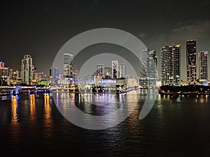 Miami city skyline panorama at dusk with urban skyscrapers and bridge over sea