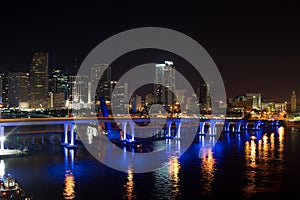 Miami city skyline panorama at dusk with urban skyscrapers and bridge over sea with reflection