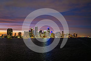 Miami city skyline panorama with urban skyscrapers over sea with reflection. Miami downtown view at night. Downtown