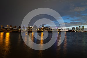 Miami night. Miami city skyline panorama with urban skyscrapers over sea with reflection.