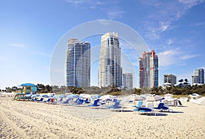 Miami South Beach with beach chairs and umbrellas , blue sky , and view of skyline condos and hotels