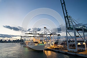 Miami, USA - March 01, 2016: cargo ship and cranes in sea port on evening sky. Maritime container port or terminal. Shipping freig