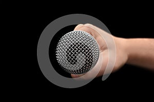 Mic - Close-up of the dynamic microphone held with one hand on an isolated black background