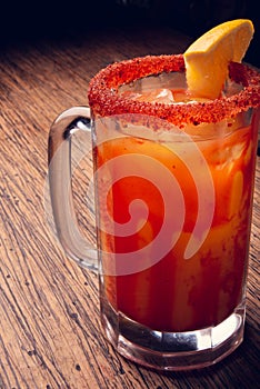 Michelada beer with tomato juice. Clamato with beer on wooden table. Mexican drink. Mexican food. photo