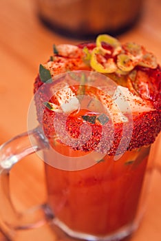 Michelada beer with tomato juice. Clamato with beer on wooden table. Mexican drink. Mexican food. photo