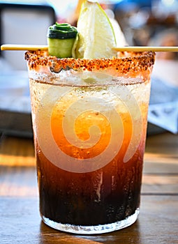 Michelada beer with tomato juice. Clamato with beer on wooden table. photo