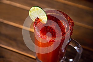 Michelada beer with tomato juice. Clamato with beer on wooden table. Mexican drink. Michelada beer with tomato juice, shrimps photo