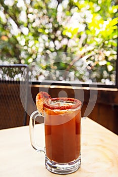 Michelada beer with tomato juice. Clamato with beer on wooden table. Mexican drink. Michelada beer with tomato juice, shrimps. photo