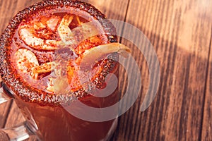 Michelada beer with tomato juice and shrimp. Clamato with beer on wooden table. Mexican drink. Vertical shot. Mexican food photo