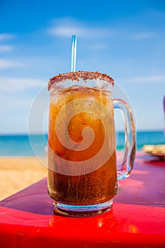 Michelada on red table Mazunte, Oaxaca, Mexico photo