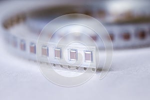 Micro Electronics Conceptual. Closeup of Tape with New SMD or Surface Mount Inductance Components in Tape Together On White photo