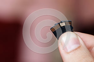 Micro sd card in human fingers on brown background with copy spa