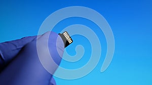 Micro SD memory card in hand close-up on blue background