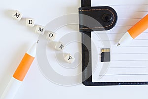 Micro-sd memory card next to an open notebook and a fountain pen. Comparison of modern memory storage and retro notebook. Modern
