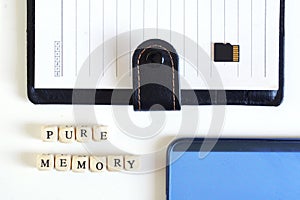 Micro SD memory card with an open notebook and a blue smartphone next to the inscription: Pure memory. Miniaturization. Modern photo