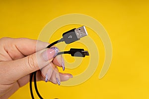 Micro USB cable in hand close-up on yellow background
