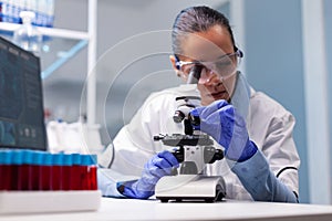 Microbiologist doctor woman analyzing vaccine results using medical microscope