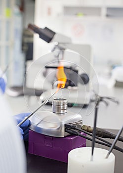 Microbiologist holding inoculation loop in flame in laboratory