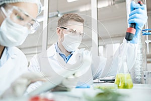 Microbiologist taking sample of solution in flask