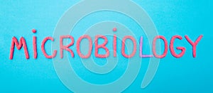 Microbiology word laid out on a blue background from red plasticine, science concept bacteriology, mycology, virology,