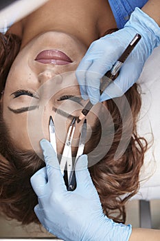 Microblading, woman drawing with pencil eyebrow shape, checking it with caliper.