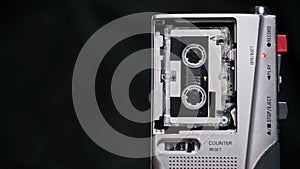 The Microcassette Spins in a Portable Handheld Recorder on Black Background