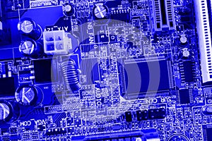 Microchip, filter, capacitors, battery, connectors on the motherboard of a modern computer blue background close macro
