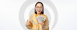 Microcredit and money concept. Stylish asian young woman in sunglasses, laughing happy, holding dollars cash, standing