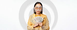 Microcredit and money concept. Stylish asian young woman in sunglasses, laughing happy, holding dollars cash, standing