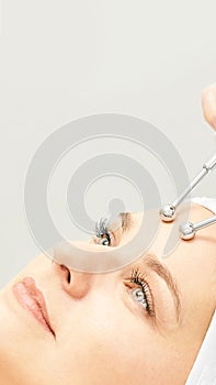 Microcurrent esthetics procedure. Beauty girl face. Cosmetology machine. Doctor hands. Two micro balls. Wrinkle reduction photo