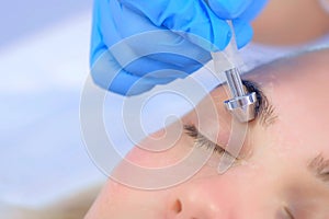 Microcurrent face treatment with hyaluronic acid gel for young woman, closeup.