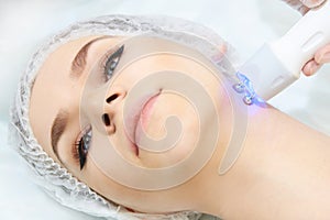 Microcurrent facial dermatology procedure. Model. Aesthetic radiofrequency treatment. Micro current cosmetology massage